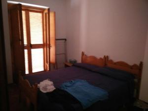 ヴィッラノーヴァ・ディ・オストゥーニにあるLa casa del portoのベッドルーム1室(木製ベッド1台、窓付)