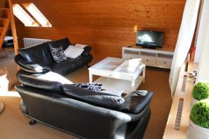 a living room with a black leather couch and a tv at Ferienwohnung Hämelschenburg in Emmerthal