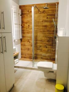 een badkamer met een toilet en een douche met houten wanden bij Piper Cytadela Apartament in Poznań
