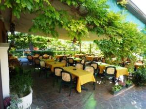 ein Restaurant mit gelben Tischen und Stühlen unter einem Sonnenschirm in der Unterkunft Al Cavallino Bianco in Tricesimo