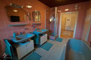 a bathroom with two blue sinks and a tub at Quilt Inn in Baumholder