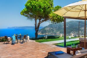 eine Terrasse mit einem Tisch und Stühlen sowie Blick auf das Wasser in der Unterkunft Villa Savvina in Skopelos