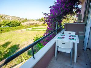 a table and chair on a balcony with purple flowers at Eleni's Studios in Katelios