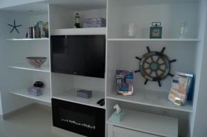Habitación con estanterías blancas y TV de pantalla plana. en Beach-Front Bahia Dorada, en Estepona