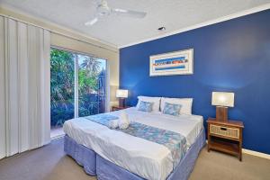 a blue bedroom with a large bed and a window at North Cove Waterfront Suites in Cairns +30 photos