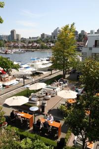 a restaurant with tables and umbrellas next to a marina at Granville Island Hotel in Vancouver