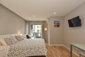 een slaapkamer met een bed en een flatscreen-tv bij Oporto Bernardes Studios - Heroísmo in Porto