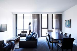 Eine Frau steht in einem Wohnzimmer mit einem Tisch in der Unterkunft Knightsbridge Canberra in Canberra