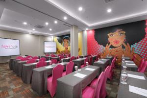 une salle de conférence avec des tables, des chaises roses et un écran dans l'établissement favehotel Sorong, à Sorong