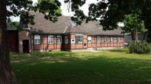 an old brick house with a green lawn in front of it at Pension Zur Eiche in Drebenstedt