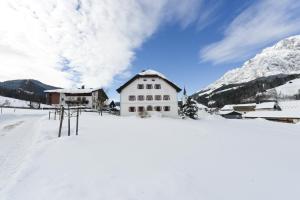 ein Haus im Schnee mit Bergen im Hintergrund in der Unterkunft Ansitz Wirtsgut - Familienappartements in den Bergen in Leogang