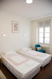 two beds in a room with a blue chair at ALBIAPPART(2) in Albi