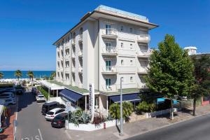 un grande edificio bianco con macchine parcheggiate di fronte di Hotel Ca' Bianca a Riccione