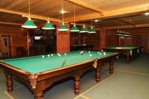 a billiard room with two pool tables and lights at Rahat Hotel in Aktau