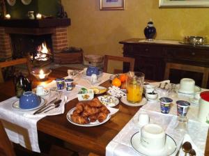 - une table avec des aliments pour le petit-déjeuner et une cheminée dans l'établissement B&B Castelvecchio, à Ferrere