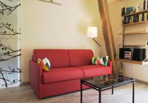 un sofá rojo en una sala de estar con mesa en La Closerie, en Marcenay