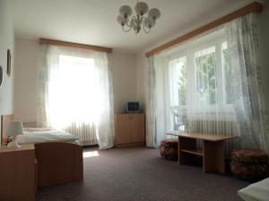 a bedroom with two beds and a window and a table at Penzion Horinka Velké Losiny in Velké Losiny