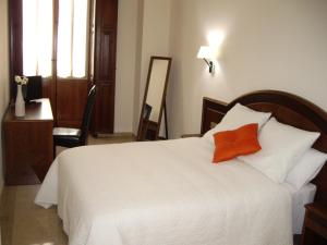 a hotel room with a bed, chair, lamp and a window at Hotel San Sebastián Hospedería in Cieza