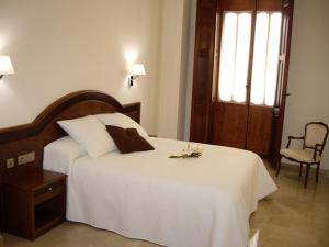 a hotel room with a bed, chair, and nightstand at Hotel San Sebastián Hospedería in Cieza