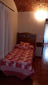 a bedroom with a bed with a red and white quilt at Apartamentos Rurales Casas de los Maestros in Talarrubias