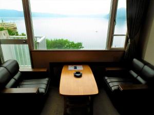 
a living room with a couch, coffee table and a window at Granvillage Toya Daiwa Ryokan Annex in Lake Toya
