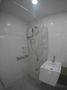 a white bathroom with a shower and a sink at Na-tub Hostel in Baan Tai