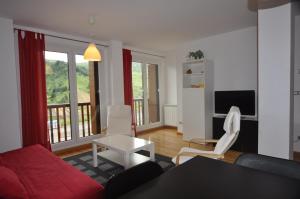 フォルミガルにあるApartamentos Tirolのリビングルーム(赤いソファ、白い椅子付)