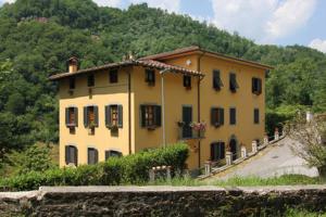 a large yellow house in front of a mountain at Apartment Poesia in Bagni di Lucca