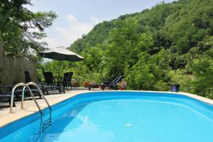 a blue swimming pool with a table and an umbrella at Apartment Poesia in Bagni di Lucca