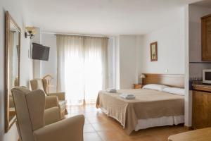 トレモリノスにあるApartamentos Edificio Caprichoのベッドとテレビが備わるホテルルームです。