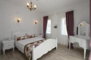 a white bedroom with a white bed and a desk at Alya Mou Butik Hotel in Çeşme