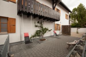 eine Terrasse mit Stühlen und einem Baum neben einem Gebäude in der Unterkunft Georg Mayer Haus in Oberstdorf