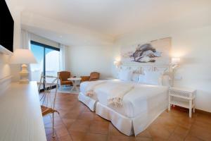 a bedroom with a large white bed with a painting on the wall at Iberostar Selection Andalucia Playa in Chiclana de la Frontera