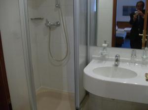 a bathroom with a shower and a sink and a mirror at Hotel Gasthaus Keune in Salzgitter