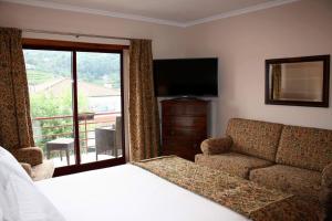 a bedroom with a bed and a couch and a television at Casa no Douro in Mesão Frio +29 photos