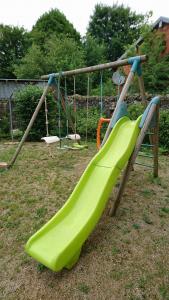 un toboggan vert dans une aire de jeux dans l'établissement Maison Familiale À Recey-Sur Ource, à Recey-sur-Ource