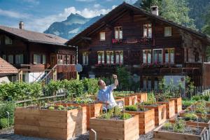 a man sitting in front of a garden in front of a house at Seilers Vintage Hotel & Spa in Kandersteg +130 photos