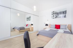 a white bedroom with a bed and a chair at InPoint Downtown Apartments near Old Town in Krakow