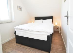 a bed with white sheets and pillows in a room at Waldsiedlung DHH MeerSeenSucht in Korswandt