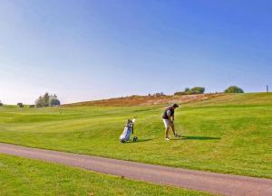 a man and a child playing golf on a golf course at Waldsiedlung DHH MeerSeenSucht in Korswandt