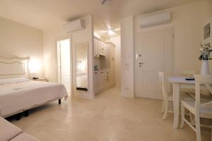 a white bedroom with a bed and a table at Garda Apartments San Vigilio Golf in Pozzolengo