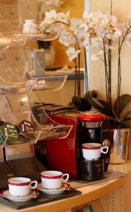 uma mesa com chávenas de café, uma torradeira e flores em Sletz Parkhotel - Superior em Gießen