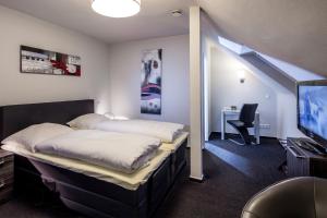 a bedroom with a bed and a desk and a tv at Hotel La Scala in Gelsenkirchen