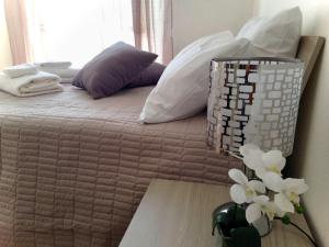 un letto con cuscini bianchi e un vaso con fiori sopra di Orchidea in Centro a Como