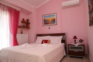 una camera con un letto bianco e una parete rosa di Athina Luxury Apartment a Keramotí