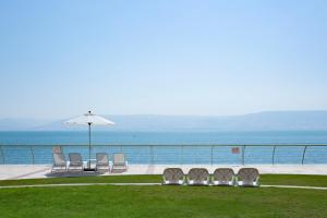 a group of chairs and an umbrella and the ocean at Gai Beach Hotel in Tiberias