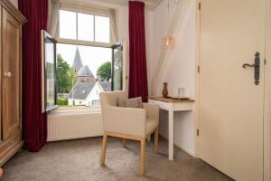 a room with a chair and a desk and a window at Hotel Restaurant Taverne in Twello