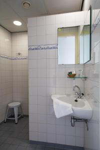 Baño de azulejos blancos con lavabo y espejo en Hotel Restaurant Taverne, en Twello