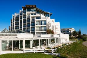 a large white building with chairs in front of it at Thalazur Port-Camargue - Hotel & Spa in Le Grau-du-Roi