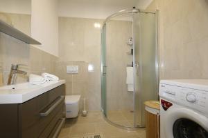 y baño con ducha, lavabo y lavadora. en Apartments Baresic, en Šilo 21 fotos más